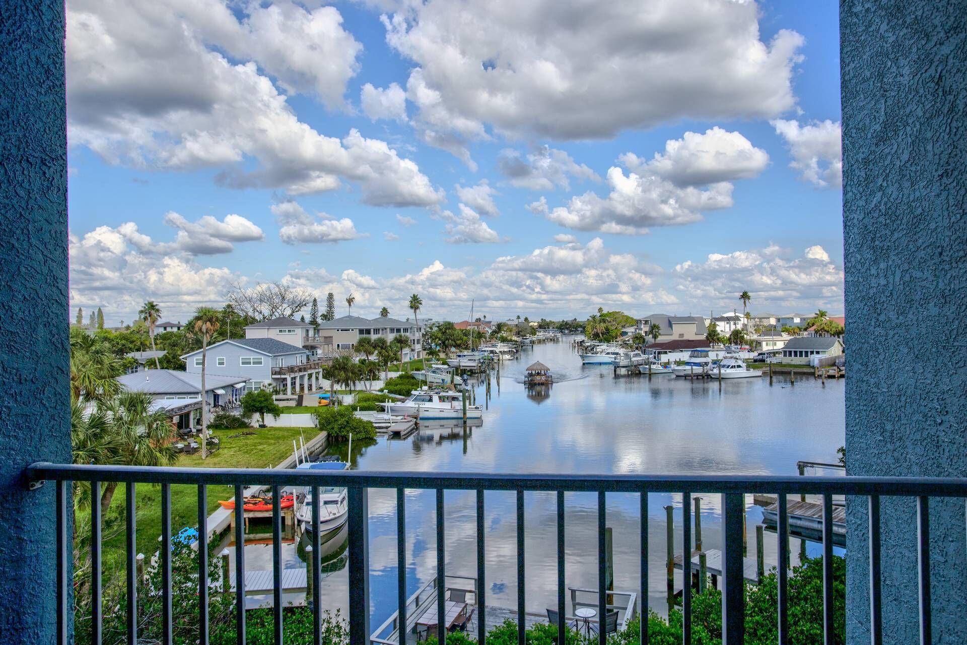 A marina with boats docked, a small island with a hut, and houses along the water.