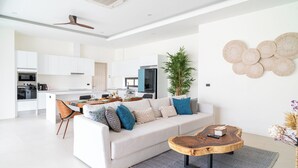 A modern living room with a sofa, coffee table, and dining area. - Villa Close to Fisherman's - KBR26 (Koh Samui)