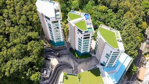 A high-rise building with multiple floors, surrounded by dense greenery. - Sea View Suite C64 in Oceana near Beach (Kamala)