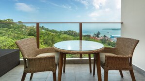 A balcony with wicker chairs and a glass table, overlooking a coastal landscape. - Sea View Suite C64 in Oceana near Beach (Kamala)