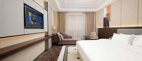 A hotel room with a bed, a desk, a chair, a TV, and a window with curtains.