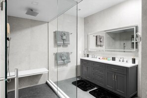 A modern bathroom with a glass shower enclosure, a vanity with dark cabinets, and a large mirror above the sink.