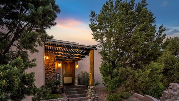 A building with a stone facade, wooden pergola, and a welcoming entrance with steps leading up to a door. - Mystic View: A 3-bedroom, 3-bath house in West Sedona close to trails & dining (Sedona)