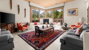 A spacious living room with a large TV, wooden ceiling, and a fireplace. - Mystic View: A 3-bedroom, 3-bath house in West Sedona close to trails & dining (Sedona)