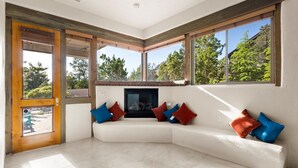 A modern living room with a built-in fireplace, large windows, and a white sectional sofa with colorful cushions. - Mystic View: A 3-bedroom, 3-bath house in West Sedona close to trails & dining (Sedona)