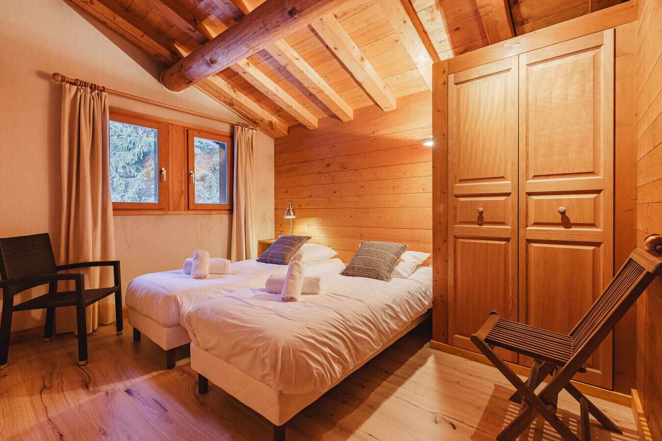 Een knus houten vertrek met een bed, een stoel en een kledingkast.
