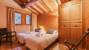 A cozy wooden room with a bed, a chair, and a wardrobe.