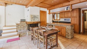 A spacious kitchen with a stone fireplace, wooden cabinets, and a dining area with a table and chairs.