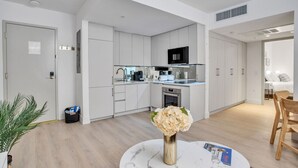 A modern kitchen with white cabinetry, a microwave, and a dining area with a table and chairs. - Vonder Miami Beach - Unit 1 (Miami Beach)