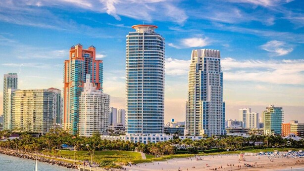 A coastal cityscape with high-rise buildings, a sandy beach, and a pier extending into the water. - Vonder Miami Beach - Unit 1 (Miami Beach)