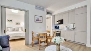 Um apartamento moderno com um quarto, área de jantar e cozinha.