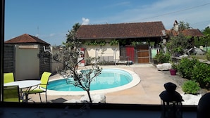 A residential property with a swimming pool, a covered patio, and a small garden area.