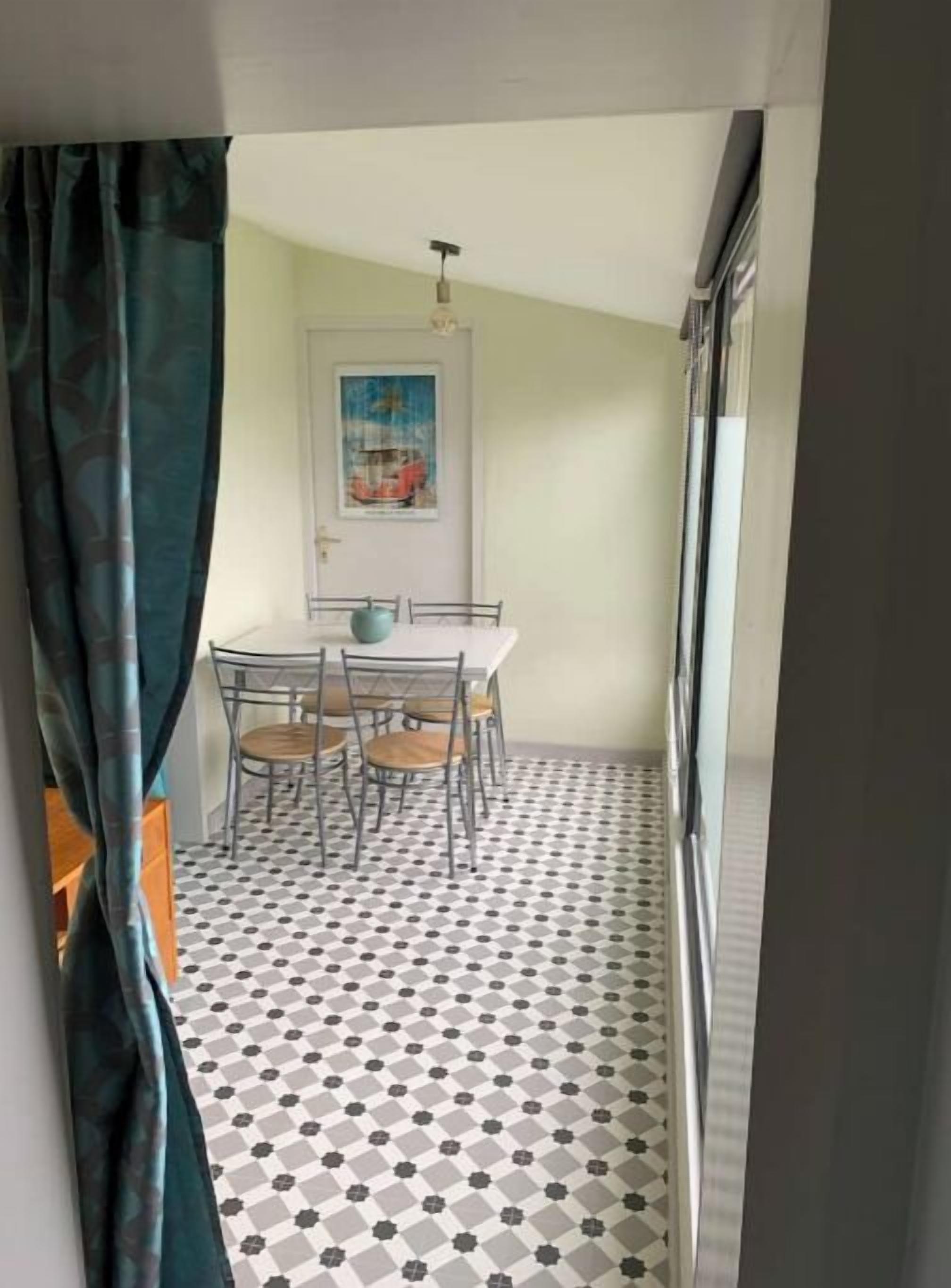 A dining area with a table and chairs, a patterned floor, and a door with a painting.