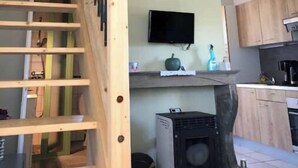 A multi-level interior with a wooden staircase, a flat-screen TV, and a kitchen area.