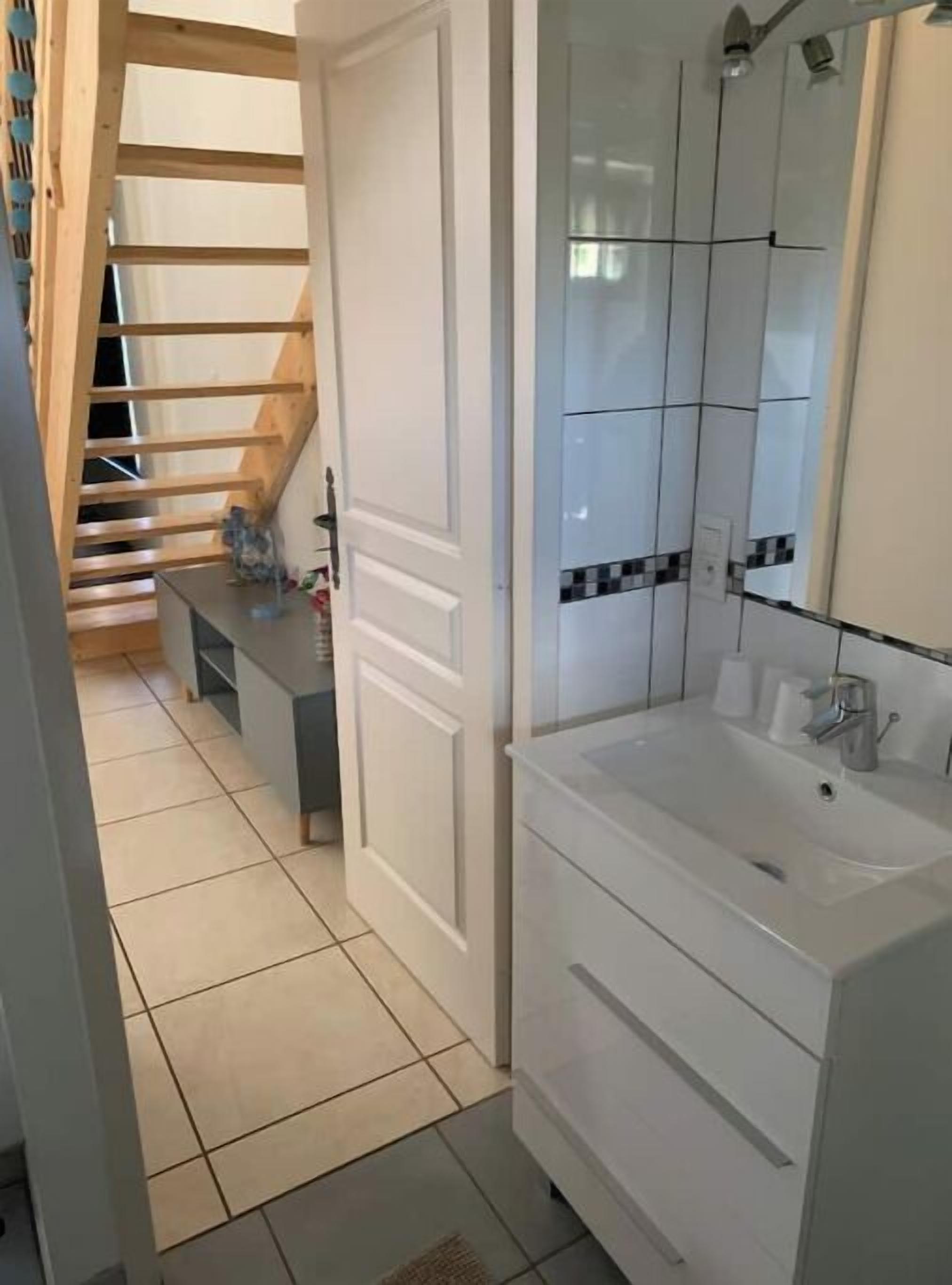 A modern bathroom with a large sink, mirror, and tiled walls.