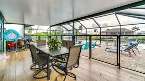 A covered patio with a table and chairs, overlooking a pool area.