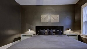 A modern bedroom with a large bed, two bedside tables, and a window with blinds. - Relaxing Retreat in Memphis Apartment (Memphis)