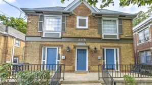 A two-story brick house with a blue front door, two windows on the upper floor, and a number '2375' above the door. - Relaxing Retreat in Memphis Apartment (Memphis)