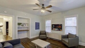 A living room with a ceiling fan, a sofa, a coffee table, two armchairs, a TV, and a bookshelf. - Relaxing Retreat in Memphis Apartment (Memphis)