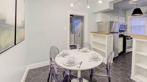 A modern kitchen with white cabinets, a built-in oven, and a dining area with a round table and chairs. - Relaxing Retreat in Memphis Apartment (Memphis)