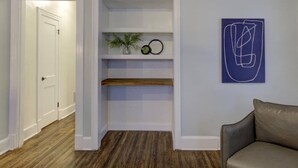 A room with a wooden floor, a white door, a built-in shelf with decorative items, and a blue abstract painting. - Relaxing Retreat in Memphis Apartment (Memphis)