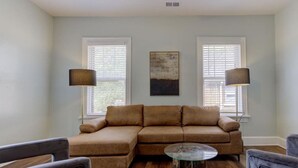 A living room with a sectional sofa, two lamps, a round coffee table, and a painting on the wall. - Sweet Stay in Memphis (Memphis)