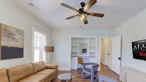 A living room with a sofa, a coffee table, and a ceiling fan. There is a hallway leading to a kitchen area. - Sweet Stay in Memphis (Memphis)