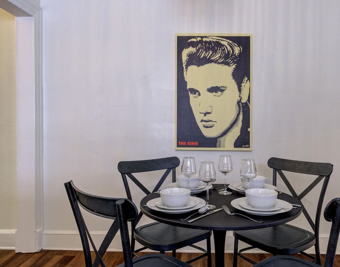 A dining area with a table set for four, black chairs, and a poster on the wall.