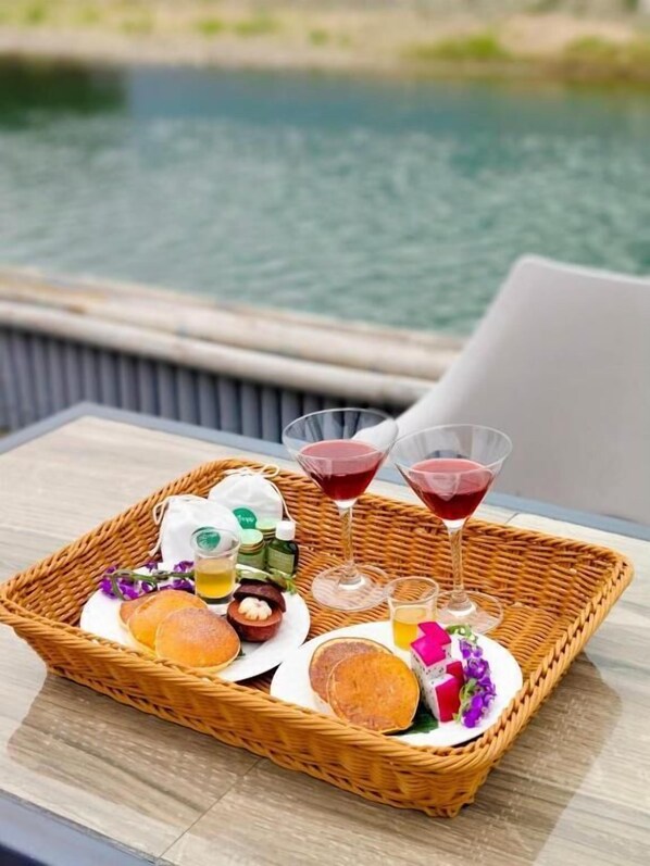 A wicker tray with food and drinks on a table by a body of water. - Family Land Camping Resort (Vang Vieng)