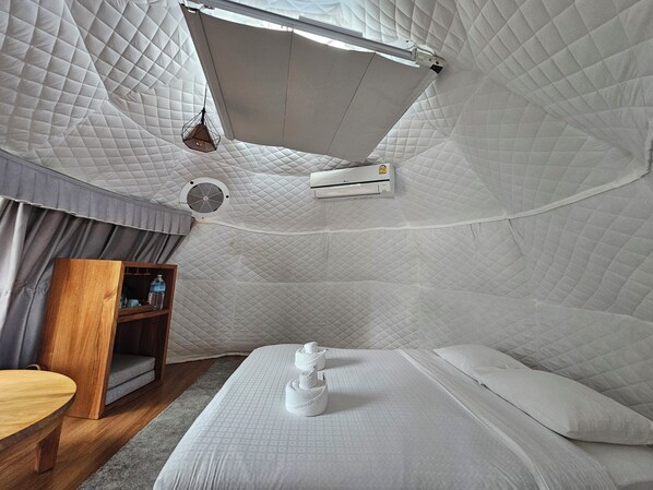 Una habitación con una cama, un armario de madera y un equipo de aire acondicionado.