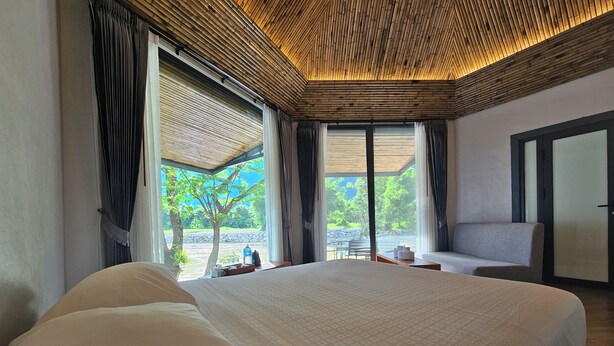 Habitación de hotel con una cama grande, un sofá y vistas a zonas verdes.