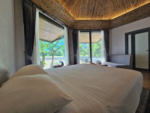Habitación de hotel con una cama grande, un sofá y vistas a zonas verdes.