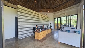 Una moderna zona de recepción con techo de madera, pared con diseño y mostrador con dos computadoras.