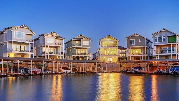 Ein Wohnhaus am Wasser mit mehreren mehrstöckigen Gebäuden, jedes mit Balkonen und einem überdachten Steg mit Booten.