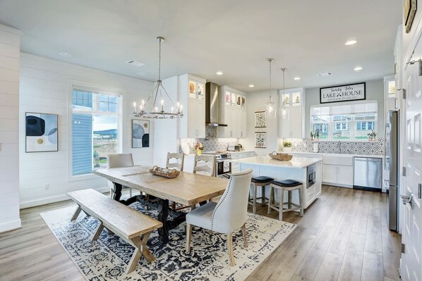 A modern kitchen with a central island, white cabinetry, and a chandelier.