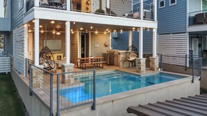Ein zweistöckiges Haus mit Swimmingpool, Sitzgelegenheiten im Freien und Lichterketten.