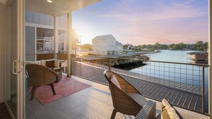 Ein Balkon mit Korbstühlen und Blick auf einen Fluss sowie Gebäude.