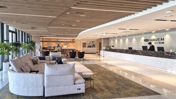Un moderno vestíbulo de hotel con mostrador de recepción, zona de estar y servicio de café y té.