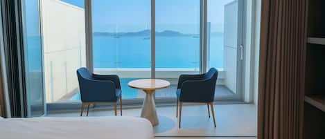 A hotel room with a large balcony, two chairs, a small round table, and a bed.