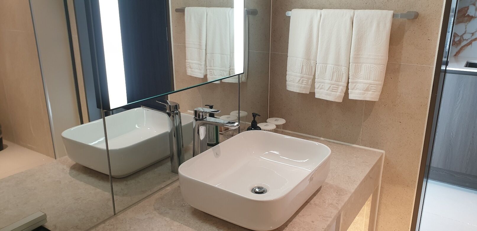 Un baño moderno con ducha envuelta en cristal, una bañera independiente y un tocador con lavabo.