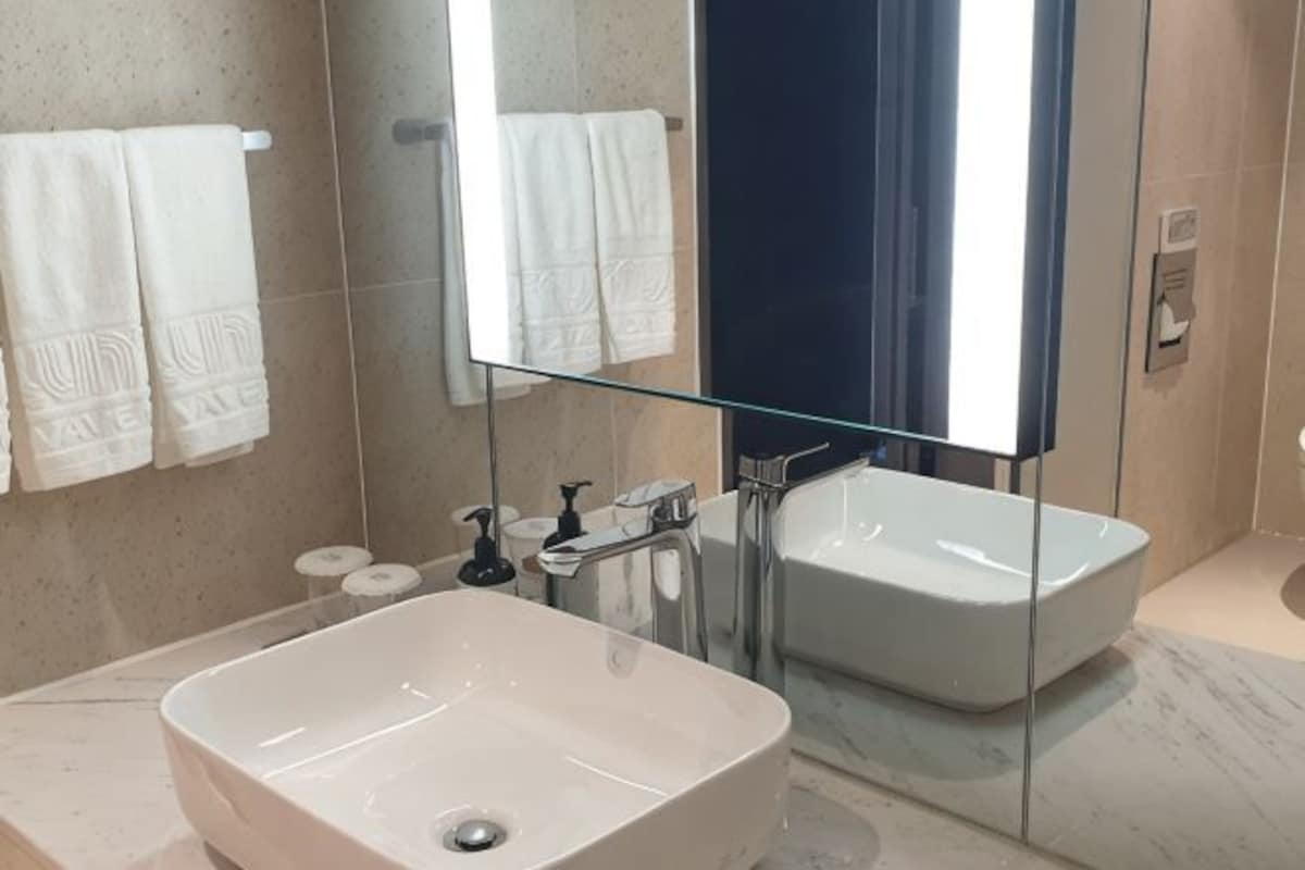 Un baño con un espejo grande, un lavamanos rectangular y una bañera.
