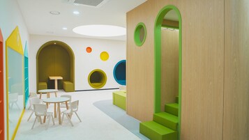 Un área infantil moderna y de colores vivos, con asientos redondos y una escalera.