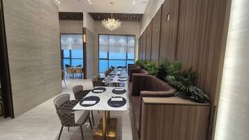 Uma sala de jantar moderna com uma mesa comprida, cadeiras estofadas e uma parede de destaque em madeira.