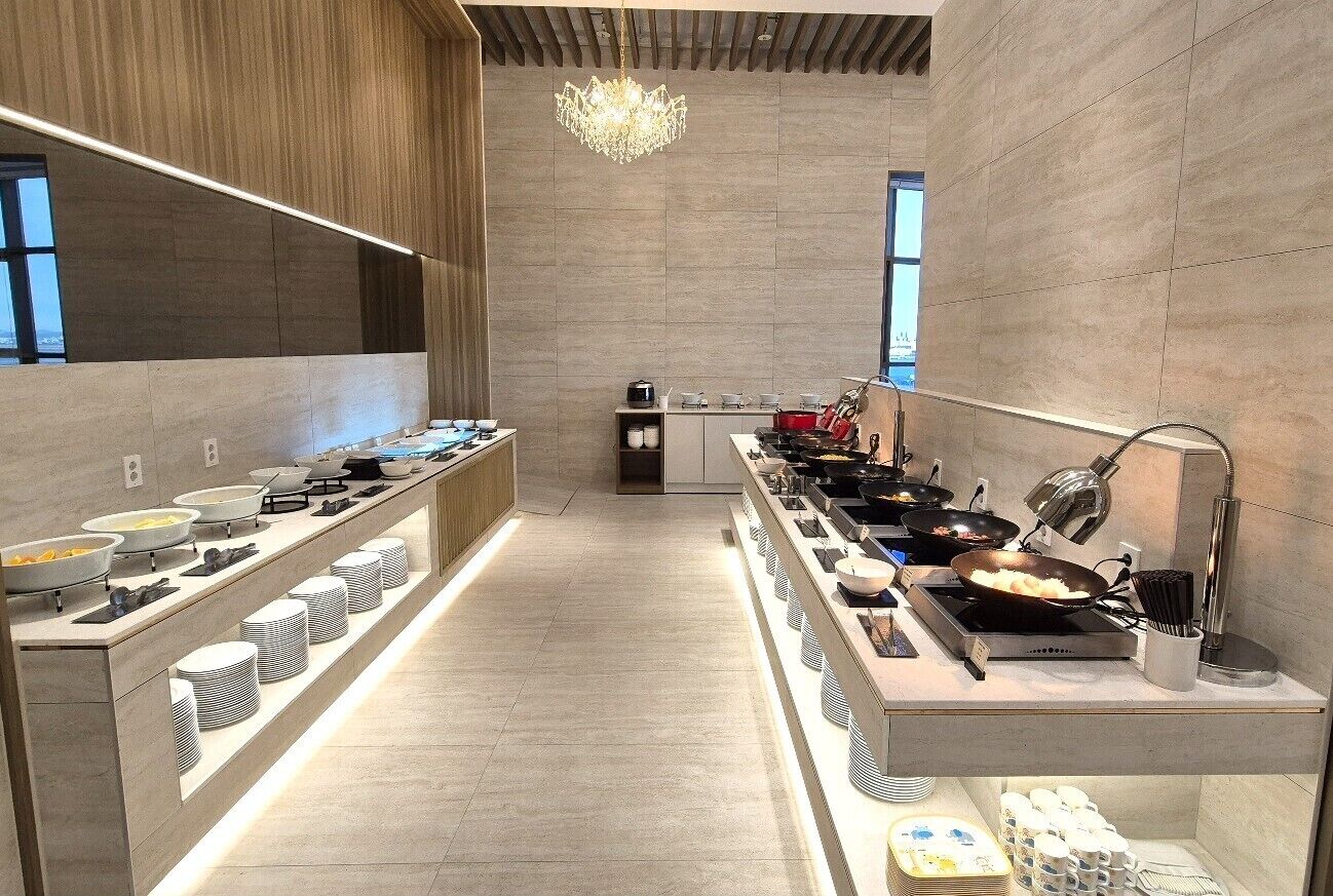 Une cuisine moderne dotée de plusieurs plans de cuisson, d’un lustre et offrant une vue sur la ville.