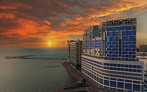 A modern high-rise hotel with a waterfront view, featuring multiple floors and a prominent glass facade. - WAVE M HOTEL EAST (Siheung)