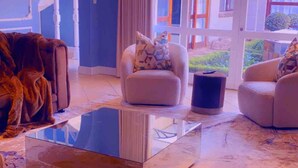 A spacious living room with a glass coffee table, a plush armchair, and a sofa.
