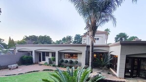 A modern house with a swimming pool, a well-maintained lawn, and a palm tree.