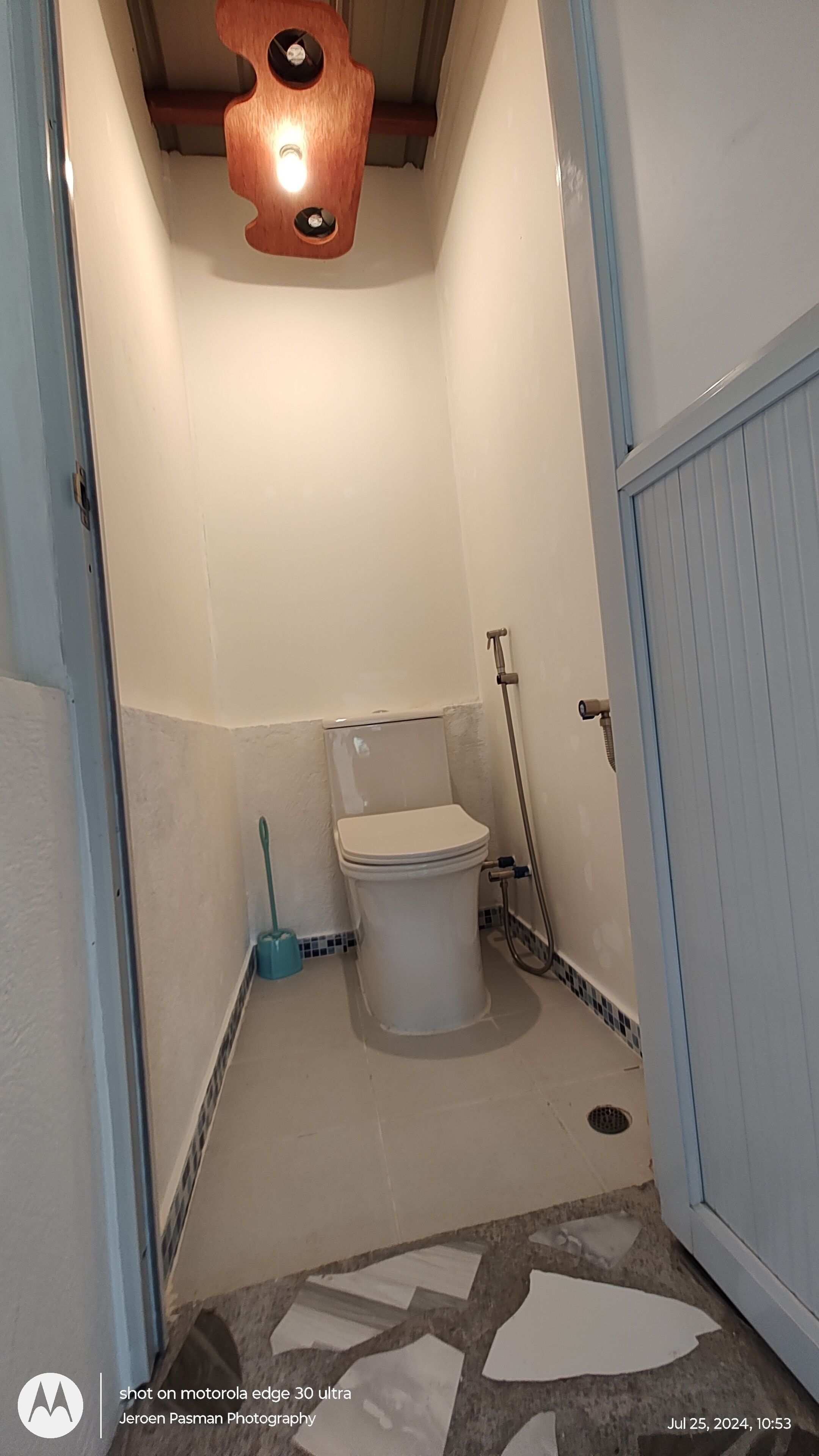 A small bathroom with a toilet, a shower, and a blue door.