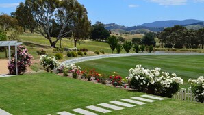 Ein gepflegter Golfplatz mit weißem Zaun, saftigem Grün und blühenden Sträuchern.