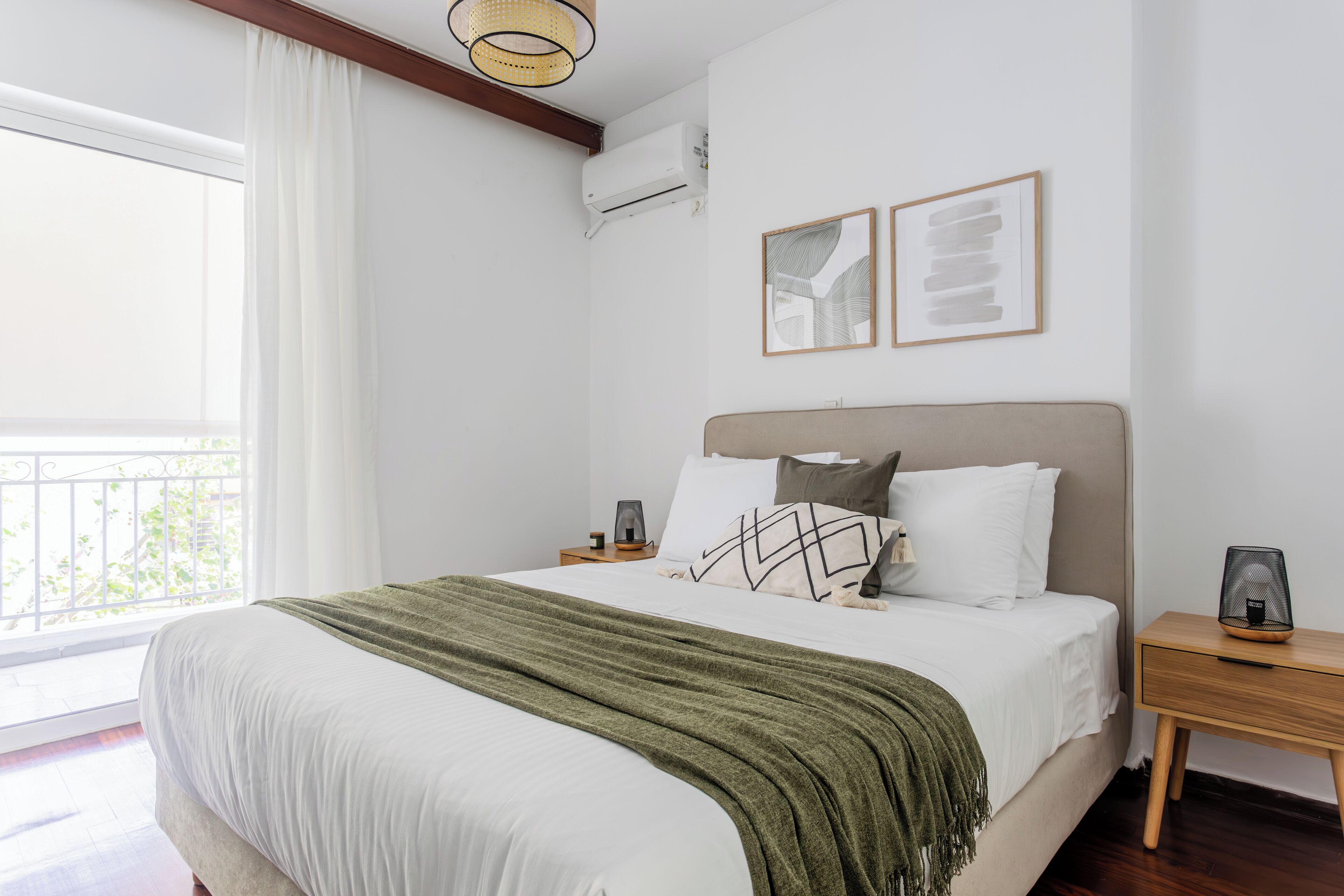 A bedroom with a bed, a nightstand, a lamp, a picture frame, and a window.